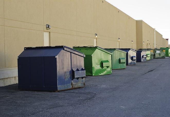 a team of workers hauls broken concrete in wheelbarrows to the dumpster in Bakersfield, CA